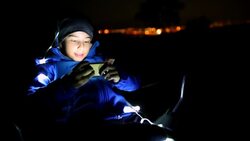 Boy playing a video game outdoors at night Stock Footage