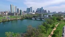 Aerial View Austin Texas Skyline Colorado River Fun Spring water activities going down low near trees with joggers on hike and bike trail Stock Footage