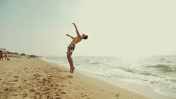 Man flips and spins a sommersault on the beach Stock Footage