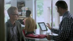 Customer brings shirt to checkout counter, swipes credit card, and signs name on iPad terminal square in modern clothing store Stock Footage
