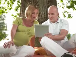 HD DOLLY: Pregnant Couple Using Tablet In The Park Stock Footage