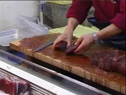 Tsukiji fish market, Tokyo, Japan, MS man slicing whale meat on chopping board . Stock Footage