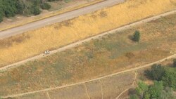 Two horseback riders travel a trail between a river and a residential area. Stock Footage