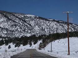 MS Snowy mountains by electricity  pole down paved road / Hooker, OK, United States  Stock Footage