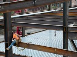 A steelworker sits on the edge of a support beam Stock Footage