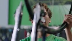 Mechanic takes bicycle wheel, places it on truing stand, and spins in bike repair shop Stock Footage