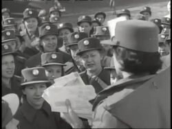A woman hands out mail to a crowd of WACs in uniform. News Clip