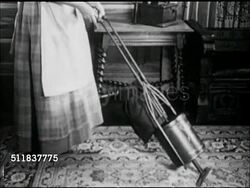 MOT: AMERICANA: TURN OF THE CENTURY REENACTMENT: Woman in period clothing (Gibson Girl) using hand squeeze 'vacuum' cleaner on rug, woman cranking Gramophone w/ scalloped edge horn. Playing music while 'vacuuming' Instructional Video
