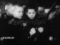 1952: CADET SCHOOL: VS Adult male officer teaching, handing boy rifle, boy pulling bolt back, MS Boys watching. VS Boys drilling outside in snow, marching in yard, making formation lines.   Iron Curtain, communists, communism. Instructional Video