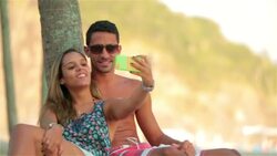 Young couple kiss and take selfies under palm tree on Brazilian beach Stock Footage
