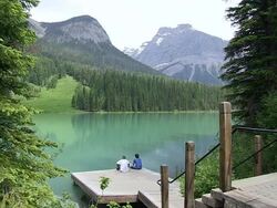 MS Two mens sitting on small wooden dock at Emerald Lake / Yoho Nationalpark, British Columbia, Canada Stock Footage