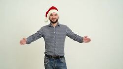 young adult beard man showing an copy space  in a hat santa claus on a grey background Stock Footage