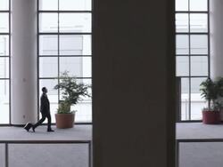  TS Business associates walking through lobby of building, one pulling a rolling briefcase / Seattle, Washington, United States Stock Footage