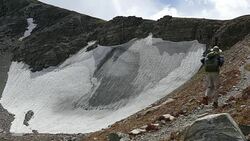 Backpacker man hiking Indian Peaks Wilderness Sawtooth Mountain snowfield Colorado Stock Footage