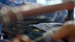 Modern shop worker counts stock and enters numbers on tablet in clothing store Stock Footage