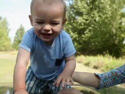 Mother and baby son playing on car hood Stock Footage