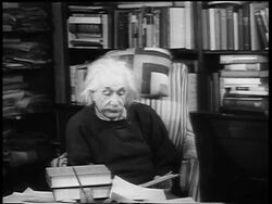 B/W 1948 Albert Einstein sitting in chair reading aloud Stock Footage