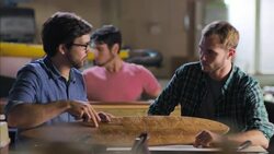 Wood shop craftsman points out design details of custom longboard to pupil Stock Footage