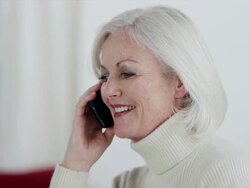 MS pan L and R  senior woman on mobile phone laughing and smiling Stock Footage