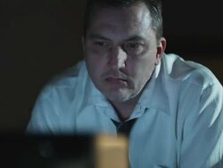 man in a shirt and tie watching television in a dark room Stock Footage