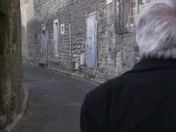 A historian strolls down an alley within the curved city walls of Saint Remy de Provence. Stock Footage