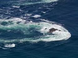 Aerial medium shot riptide off coast of Orsay Island / zoom out wide shot Orsay Island and lighthouse / Hebrides, Scotland Stock Footage
