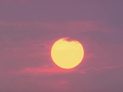 Wide shot fiery sunset with purple clouds passing over sun / New Orleans Stock Footage