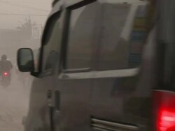 Traffic drives along road in Yogjakarta coated in volcanic ash after eruption of Merapi volcano; Central Java, Indonesia. 30 October 2010 / AUDIO Stock Footage