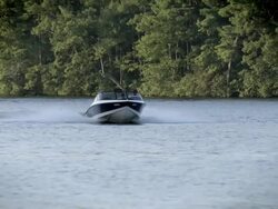 Motorboat (ski boat) on wooded lake headed straight for camera.  Slow motion. Stock Footage