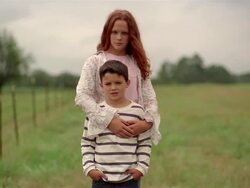 Medium shot selective focus zoom in portrait of girl with her arm around younger boy / looking at CAM Stock Footage