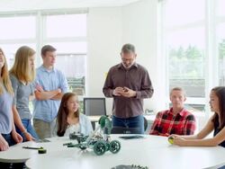MS female student in discussion with teacher and classmates around table in high school robotics class. Stock Footage