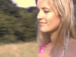 Woman walknig through field, carrying bag, UK Stock Footage