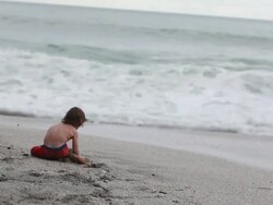 MS Little boy sitting on beach facing waves / Montezuma, Puntarenas, Costa Rica Stock Footage