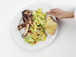 CU Woman hand entering setting down round white plate with lettuce salad and grilled chicken / Omaha, Nebraska, United States Stock Footage