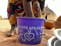CU, Woman mixing grain in bucket, low section, Niamey, Niger Stock Footage
