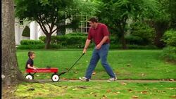 A father pulls his son through their neighborhood in a red wagon. Stock Footage