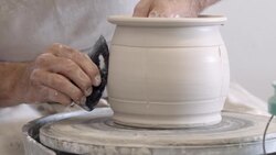 potter hand carves grooves into wet clay of freshly formed pot in pottery studio Stock Footage