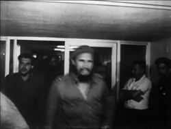 B/W 1960s Che Guevara + Fidel Castro exiting building thru crowd / newsreel Stock Footage