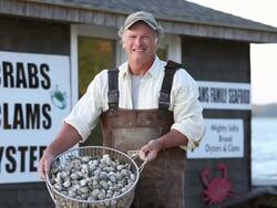 MS Portrait of Smiling Waterman Holding Basket of Fresh Oysters in Front of Seafood Shack / Oyster, Virginia, USA Stock Footage