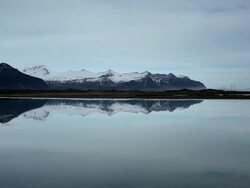 WS View of Calm surface of lagoon reflecting sky and snow covered mountain / Iceland  Stock Footage