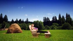 A pregnant woman relaxes in a rocking chair in a woodland meadow. Stock Footage