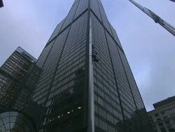 Low Angle static - An American flag and a Chicago flag wave in front of Willis Tower in Chicago, Illinois. / Chicago, Illinois, USA Stock Footage