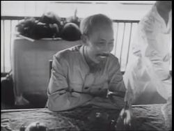 B/W 1960s Ho Chi Minh smiling + nodding head sitting at table on patio / North Vietnam Stock Footage
