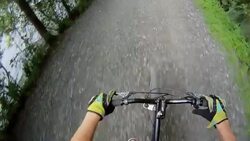 A cyclist steers his bike down a rocky mountain path and through a mud puddle. Stock Footage
