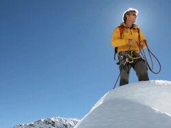 Mountaineer reads map on snowy ridge crest, looks off Stock Footage