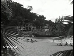 1940: MAP: Caribbean area. CARIBBEAN: WS Beach w/ residential houses BG. Cargo ship in port. Island  town houses in valley. US Battleships on ocean. WS US Aircraft carrier. XWS Three aircraft carriers silhouetted on ocean skyline. Instructional Video