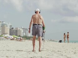WS Rea view of man with metal detector walking on beach / South Beach, Miami, Florida, USA Stock Footage