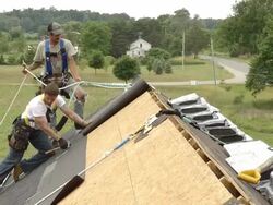MS Two workers unrolling weather seal on roof of red building / Chelsea, Michigan, United States Stock Footage
