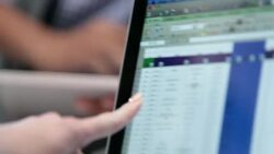 Assertive businesswoman points at spreadsheet data on laptop-computer screen, hip young businessman scans tablet in background Stock Footage