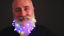 Senior adult man with a beard in black T-shirt elegant hat of Santa Claus looking at the camera shakes his head and fun Stock Footage